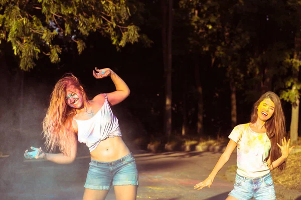 Two gorgeous young woman friends having fun with exploding Holi — Stock Photo, Image