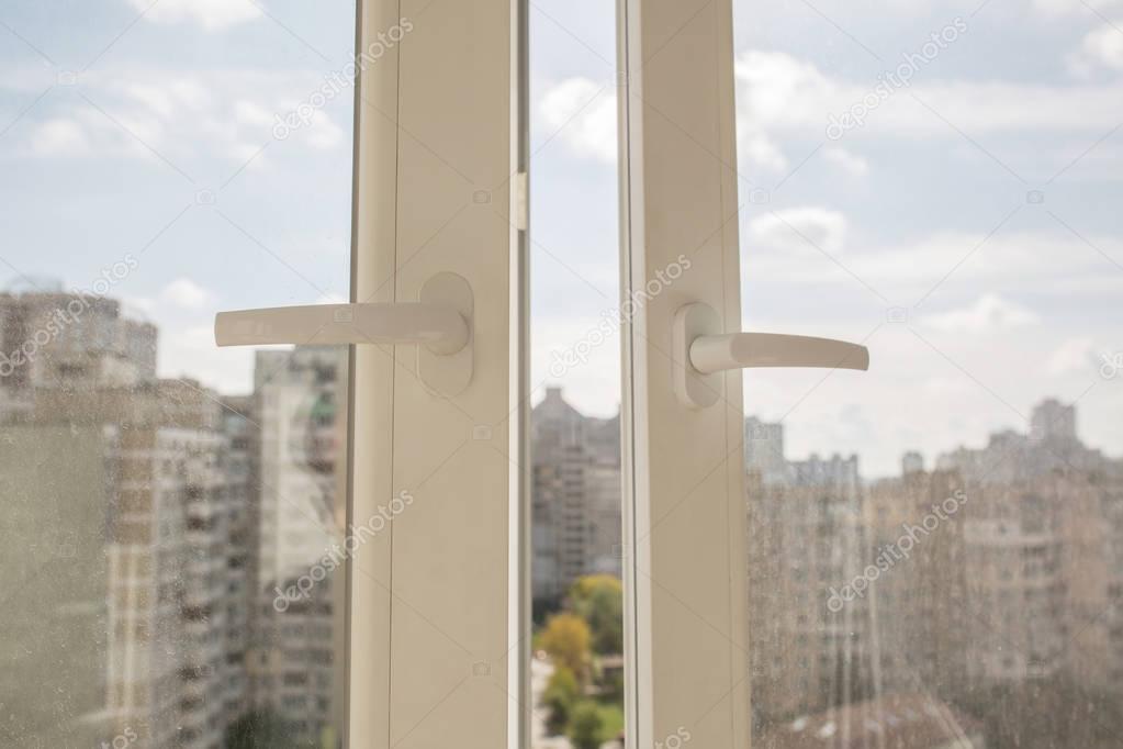 Opened white plastic window with the background of multi-storey 