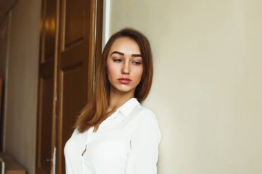 Beyaz gömlekli duvara poz romantik esmer kadın