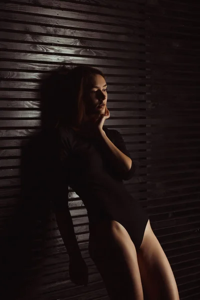 Sensual jovem mulher em lingerie preta posando perto da parede de madeira — Fotografia de Stock