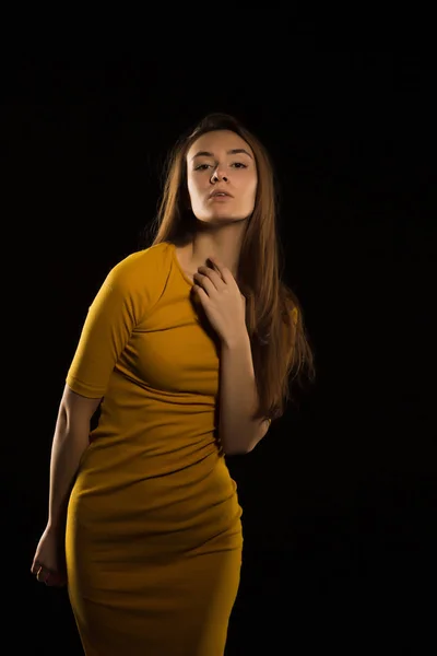 Stylish young woman with long hair in motion posing in yellow dr. — стоковое фото