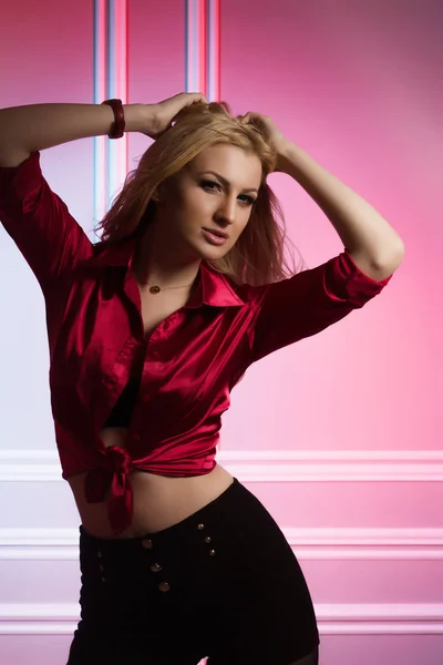 Sexy junge Dame in seidenroter Bluse posiert im Studio auf dem roten a — Stockfoto