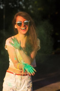 Yeşil Holi tozu ile oynayan güneş gözlüğü neşeli esmer kız