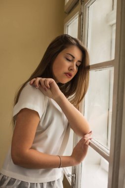 Pencerenin önünde poz beyaz bluz giyen ihale esmer modeli
