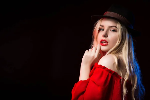 Сексуальная блондинка в красной блузке и коричневой шляпе позирует в студии — стоковое фото