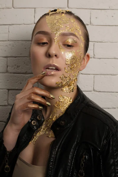 Gorgeous young woman with golden foil on her face, hair and neck — Stock Photo, Image