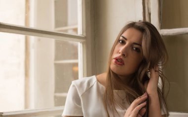 Pencerenin önünde poz beyaz bluz giyen güzel esmer kadın