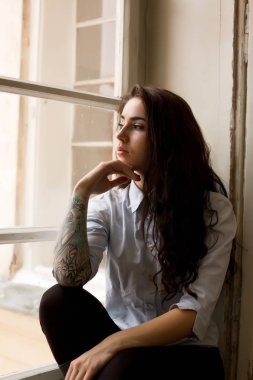 Şanlı esmer kadın kıvırcık saçlı ve onun kolundaki dövme 