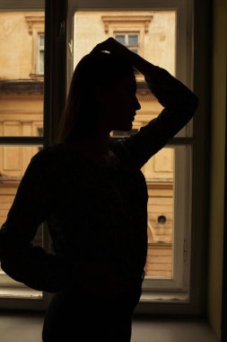 İnce model ayakta pencereden silüeti