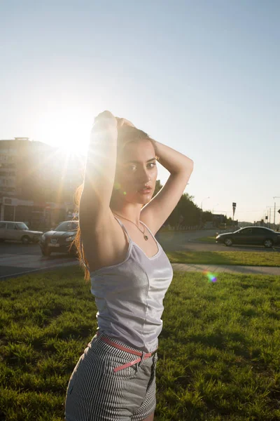 Stijlvolle brunette jonge model poseren in de stralen van de zon bij zonsondergang in — Stockfoto