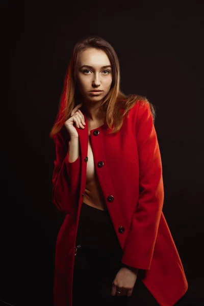 Fashionable young woman in trendy red coat clothed on the naked — Stock Photo, Image