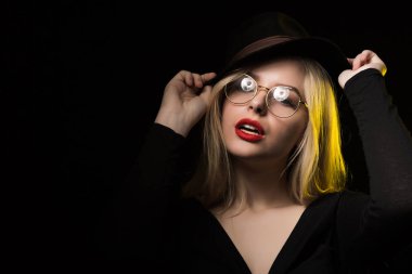 Genç kadının giydiği siyah bluz, şapka ve gözlük, posi çarpıcı