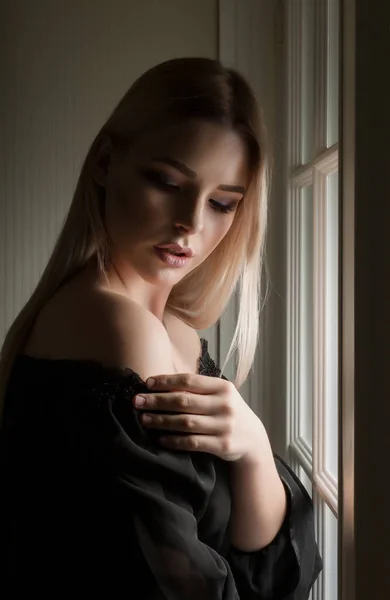 Fashionable blonde lady with naked shoulders posing in the dark — Stock Photo, Image