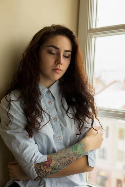 Ładna Brunetka modelu z kręconymi włosami i tatuaż na jej ramieniu — Zdjęcie stockowe
