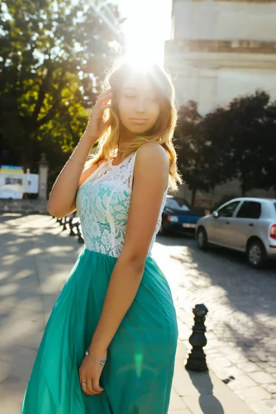 Милая блондинка в кружевном платье позирует в солнечных лучах на улице — стоковое фото