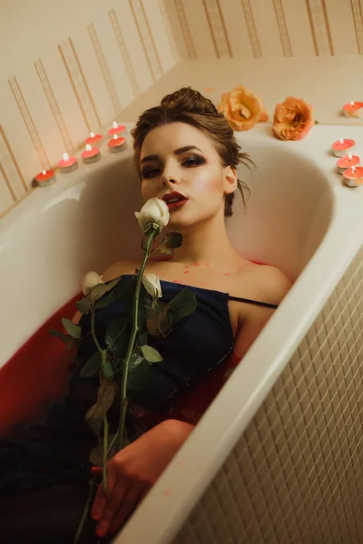 Krásné blondýnce bere koupel s červenou vodou a svíčky, h — Stock fotografie