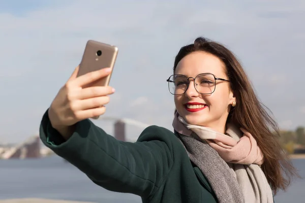 Positive brunette girl tourist taking a selfie photo on a coast — Stock Photo, Image
