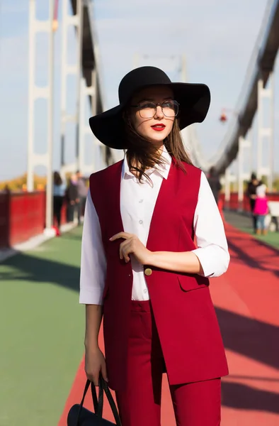 Menina morena vestida na moda em pantsuit vermelho e chapéu preto posin — Fotografia de Stock