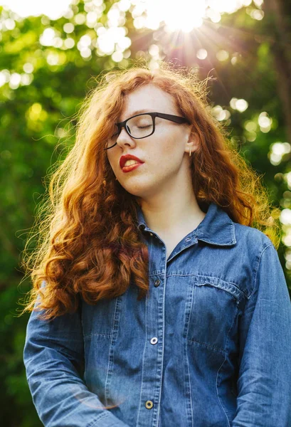 Amável vermelho cabelos jovem modelo em óculos posando em raios de sol um — Fotografia de Stock