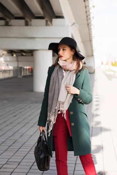 Femme brune élégante en manteau vert et chapeau noir posant à la — Photo