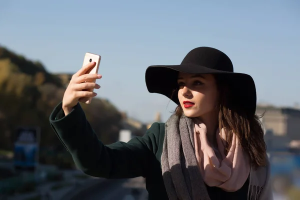 Stylish brunette girl tourist in hat taking a selfie photo in su — Stock Photo, Image