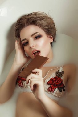 Baştan çıkarıcı genç model akşam makyaj ile süt ile bir banyo alır