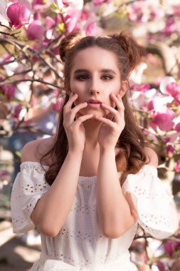 Harika esmer kız çiçek açan Manolya ağacında yakınındaki poz