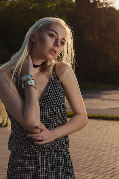 Glamorösa blond modell i svart Sparkdräkt poserar i staden i solen — Stockfoto