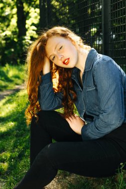 İnanılmaz Kızıl saçlı kız ormanın, güneş ışınlarının poz mavi kot gömlek