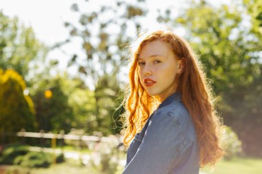 Zarif kırmızı saçlı kız güneş parlamayı poz sokak portresi. Metin için yer