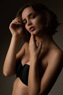 Harika bir kız karanlık stüdyoda iç çamaşırı giyer.