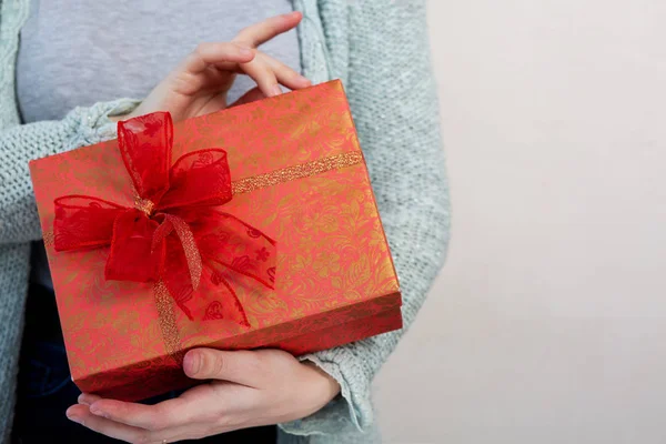 Woman's hands holding gift box over a grey background — Stock Photo, Image