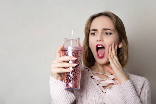 Surprised girl holding glass of juice — Stock Photo, Image
