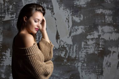 Güzel esmer bir kadının dramatik portresi çıplak omuzlu örülü bir kazak giyiyor. Metin için boşluk