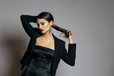 Parlak saçlı, kırmızı dudaklı çekici kadının stüdyo portresi ipek elbise ve ceket giyer. Boş boşluk