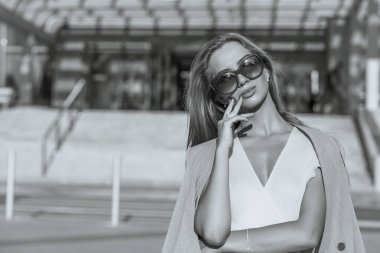 Uzun saçlı havalı genç manken güneş gözlüğü ve ceket giyiyor. Monokrom rengi. Boş boşluk