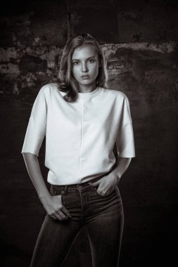 Karanlık arka planda poz veren sıradan giyinmiş güzel bir kadın için deneme çekimi. Siyah ve beyaz tonlama