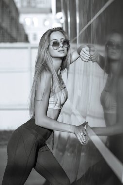 Spor kıyafetli baştan çıkarıcı sarışın kadın tenis kortunda poz veriyor. Siyah ve beyaz renk