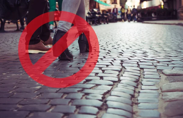 Closeup shot of feet of people walking down the street with prohibited sign. Space for text