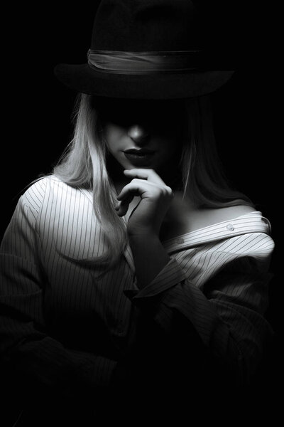Wonderful woman wearing striped blouse and hat posing with shadow on her face. Black and white color