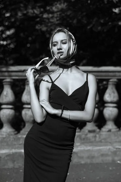 Street portrait of attractive blonde model with curly lush hair wears dress. Woman walks in sunny day at the street in Kyiv.  Monochrome toning