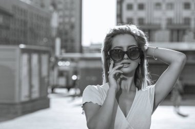 Caddede yürüyen, gözlüklü, sevimli genç bir mankenin moda portresi. Boşluk. Monokrom rengi