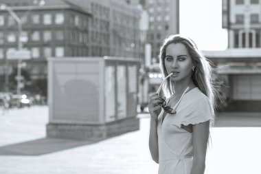 Baştan çıkarıcı, uzun saçlı, güneş gözlüğü takan ve kameraya bakan sarışın manken. Boşluk. Tek renkli portre