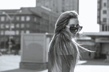 Caddede yürüyen gözlüklü sevimli genç bir kadının moda portresi. Boşluk. Tek renkli portre