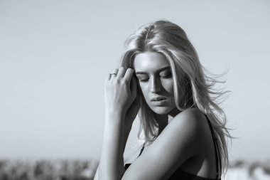 Mükemmel makyajlı ve akşam güneşinde poz veren çekici sarışın bir kadının sokak portresi. Mesaj için yer var. Tek renkli tonlama