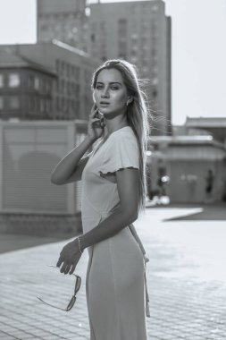 Uzun saçlı, güneş gözlüğü takan, güneş ışığında poz veren muhteşem mavi gözlü manken.