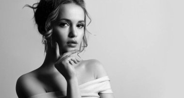 Siyah ve beyaz, kıvırcık saçlı ve çıplak omuzlu zarif bir genç kadın portresi. Metin için boşluk