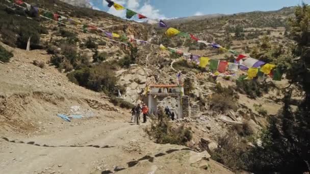 MANANG, NEPAL - CIRCA, 2019: Turistas trekking por puertas blancas en camino rocoso — Vídeos de Stock