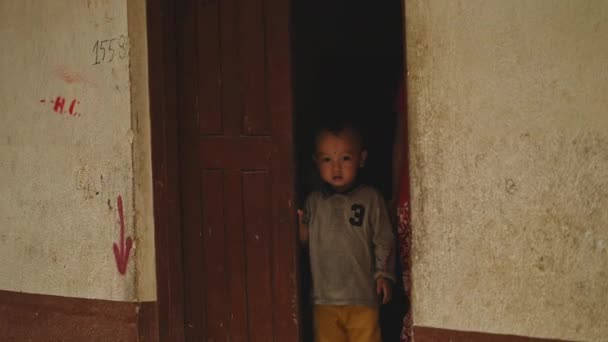 KATHMANDU, NEPAL - CIRCA, 2019 : Petit garçon nepali debout dans une porte, regarde à l'extérieur — Video