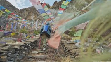 Nepal 'deki Milarepa mağarasında asılı renkli bayrakların arasına bir turist taşındı